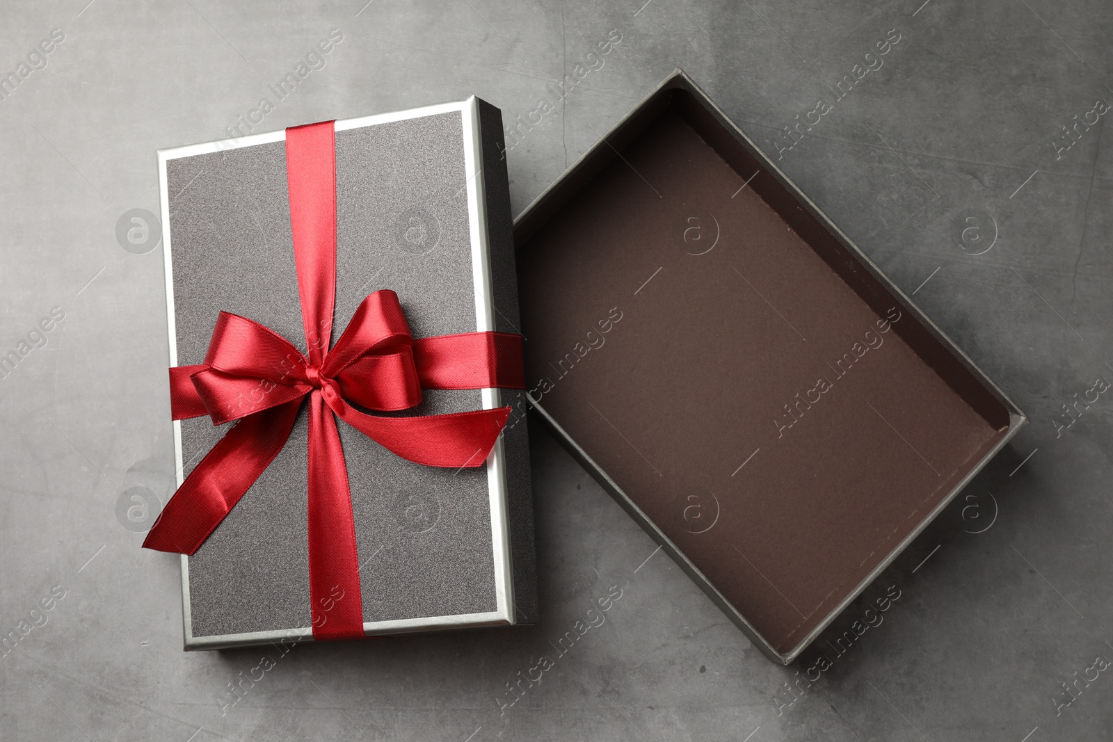 Opened gift box with beautiful lid on grey table, top view Photo of Opened gift box with beautiful lid on grey table, top view
