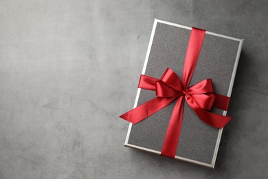 Photo of Gift box with beautiful bow on grey table, top view. Space for text