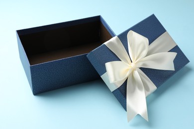 Photo of Opened gift box with beautiful lid on light blue background, closeup