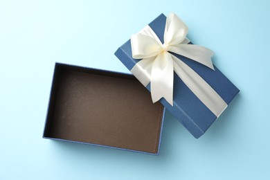 Photo of Opened gift box with beautiful lid on light blue background, top view