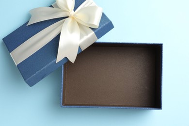 Photo of Opened gift box with beautiful lid on light blue background, top view