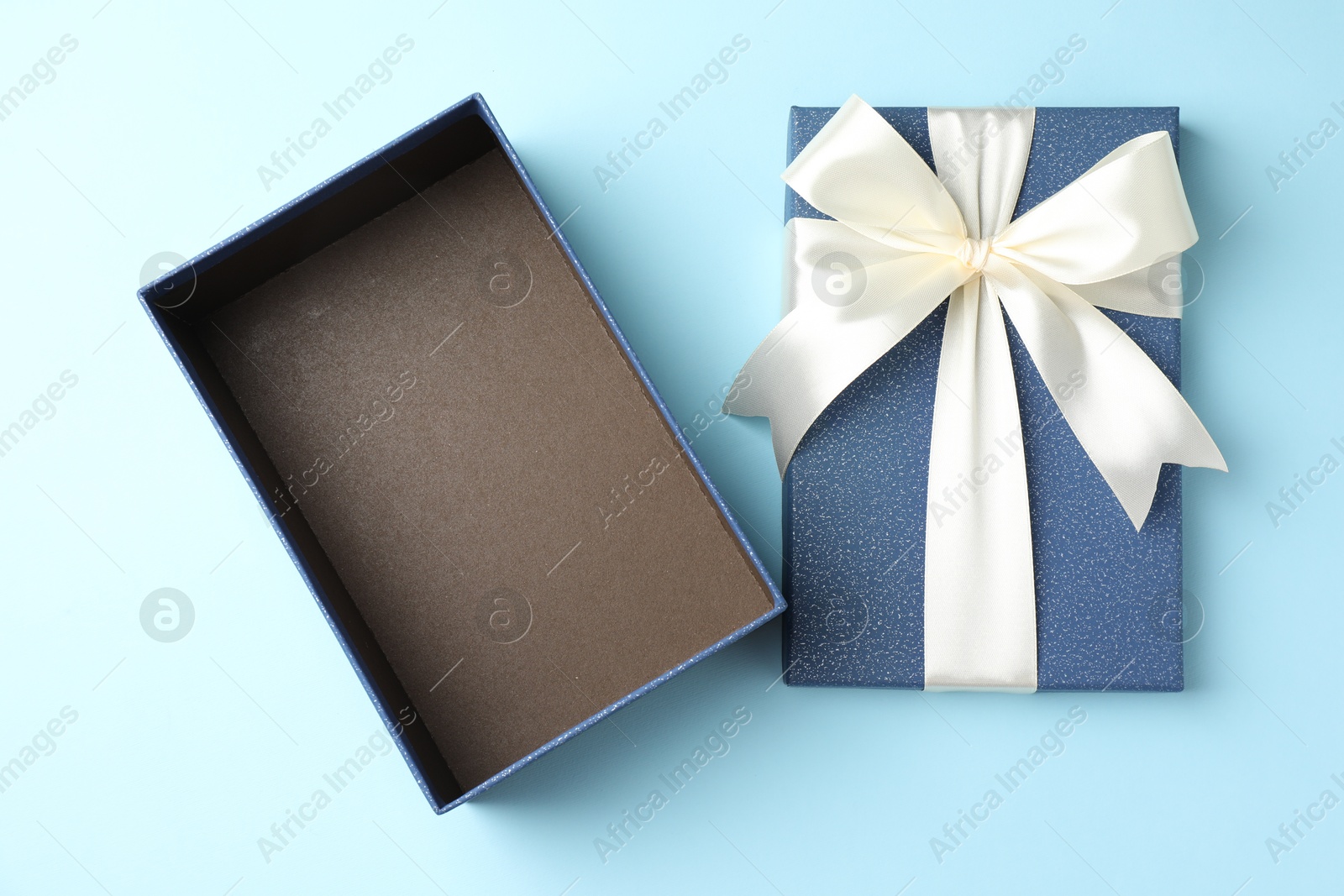 Photo of Opened gift box with beautiful lid on light blue background, top view