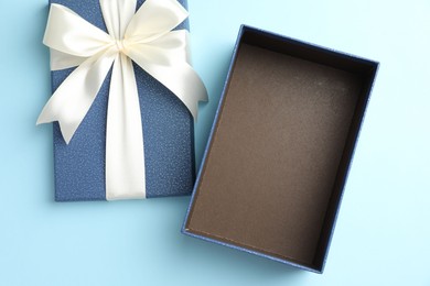 Photo of Opened gift box with beautiful lid on light blue background, top view