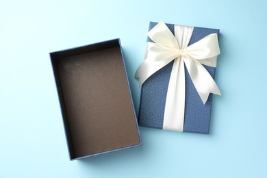 Photo of Opened gift box with beautiful lid on light blue background, top view