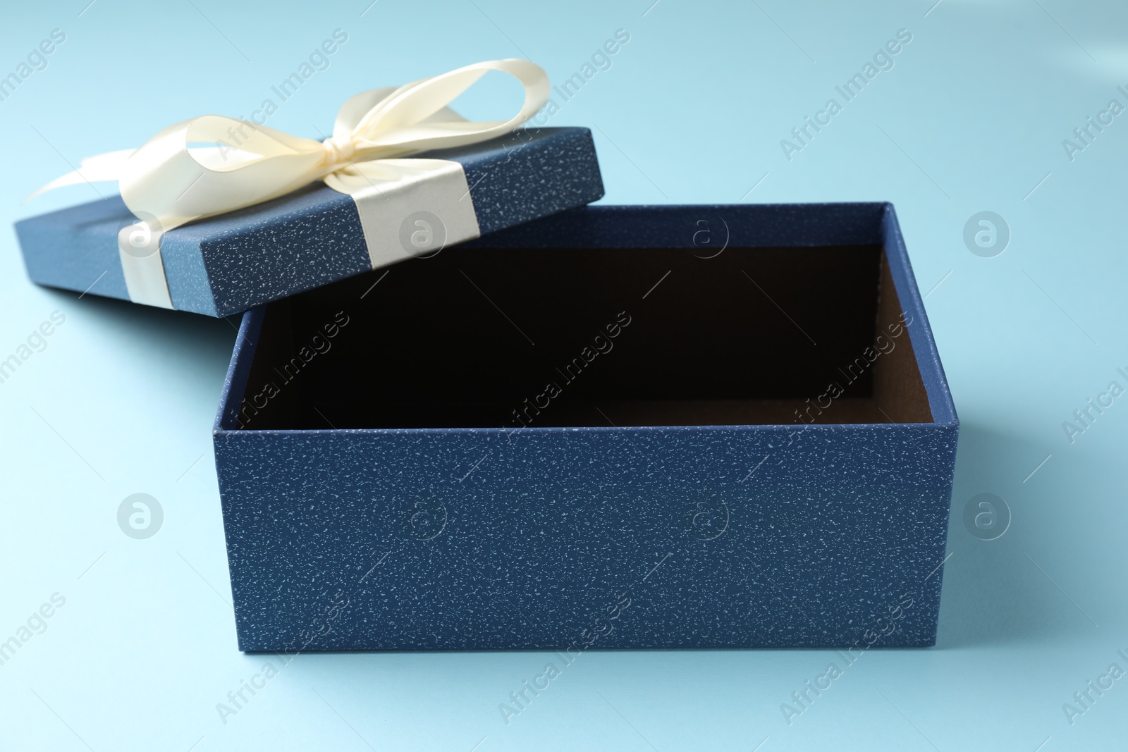 Opened gift box with beautiful lid on light blue background, closeup Photo of Opened gift box with beautiful lid on light blue background, closeup