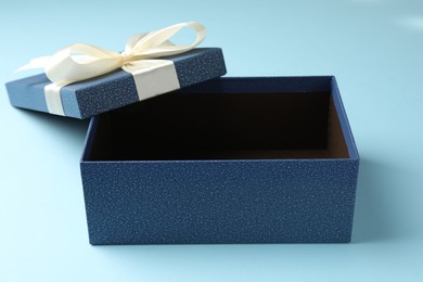 Photo of Opened gift box with beautiful lid on light blue background, closeup