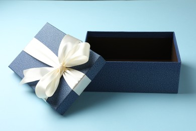 Photo of Opened gift box with beautiful lid on light blue background, closeup
