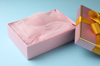 Photo of Opened gift box with beautiful lid on light blue background, closeup