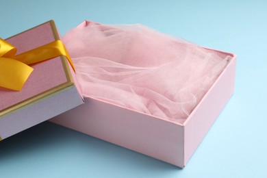 Photo of Opened gift box with beautiful lid on light blue background, closeup
