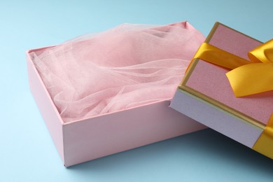Photo of Opened gift box with beautiful lid on light blue background, closeup