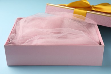 Photo of Opened gift box with beautiful lid on light blue background, closeup