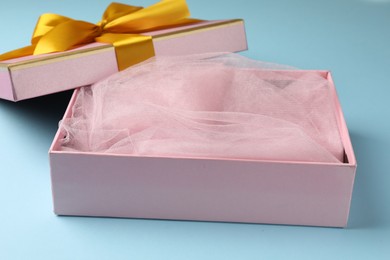 Photo of Opened gift box with beautiful lid on light blue background, closeup