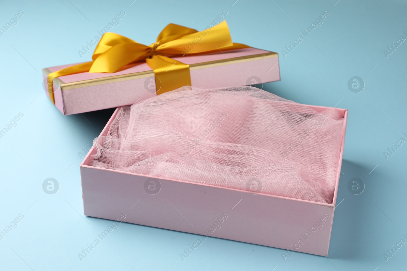 Photo of Opened gift box with beautiful lid on light blue background, closeup