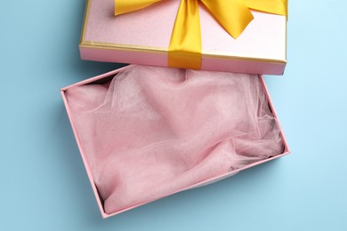 Photo of Opened gift box with beautiful lid on light blue background, top view