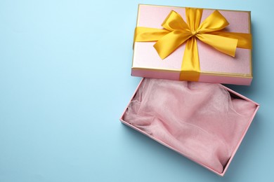 Photo of Opened gift box with beautiful lid on light blue background, top view. Space for text