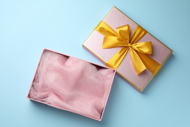 Photo of Opened gift box with beautiful lid on light blue background, top view