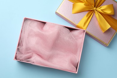 Photo of Opened gift box with beautiful lid on light blue background, top view