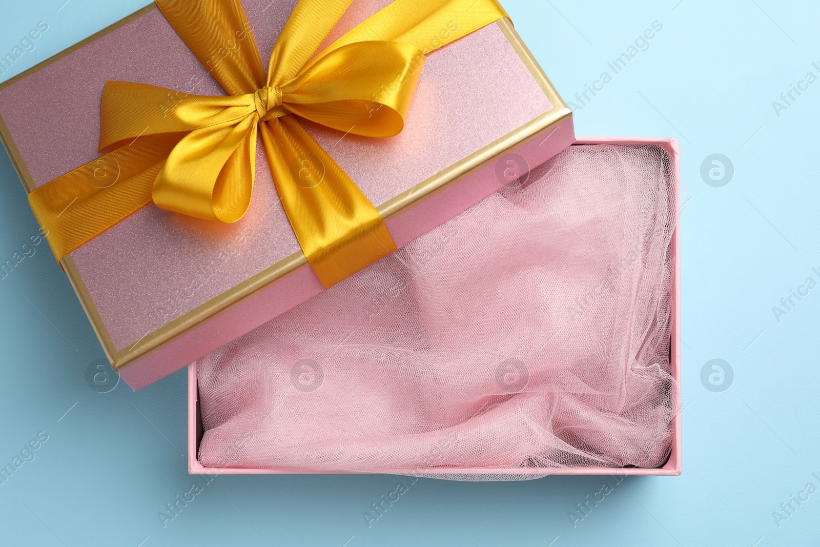 Photo of Opened gift box with beautiful lid on light blue background, top view