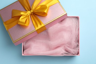 Photo of Opened gift box with beautiful lid on light blue background, top view