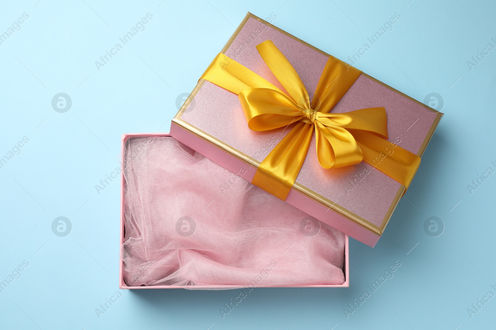 Photo of Opened gift box with beautiful lid on light blue background, top view