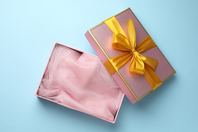 Photo of Opened gift box with beautiful lid on light blue background, top view