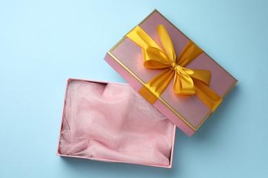 Photo of Opened gift box with beautiful lid on light blue background, top view