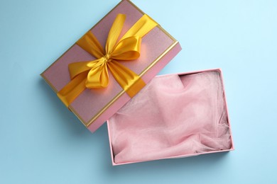 Photo of Opened gift box with beautiful lid on light blue background, top view