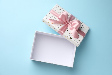 Photo of Opened gift box with beautiful lid on light blue background, top view