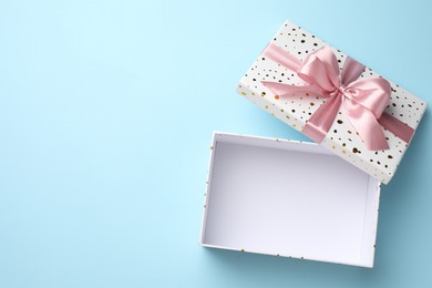 Photo of Opened gift box with beautiful lid on light blue background, top view. Space for text