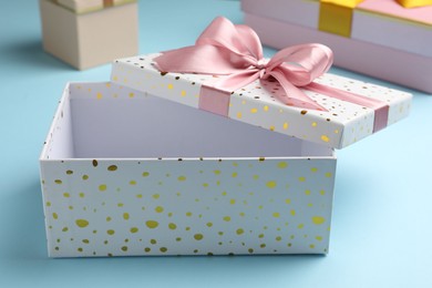 Photo of Opened and closed gift boxes on light blue background, closeup