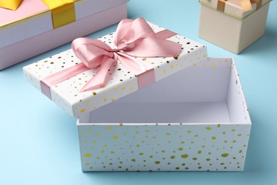 Photo of Opened and closed gift boxes on light blue background, closeup