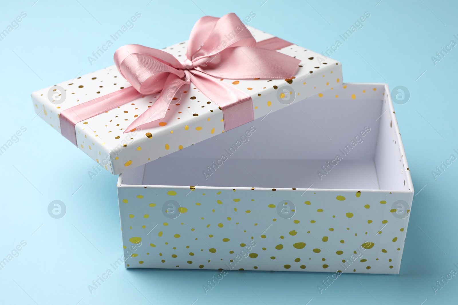 Photo of Opened gift box with beautiful lid on light blue background, closeup