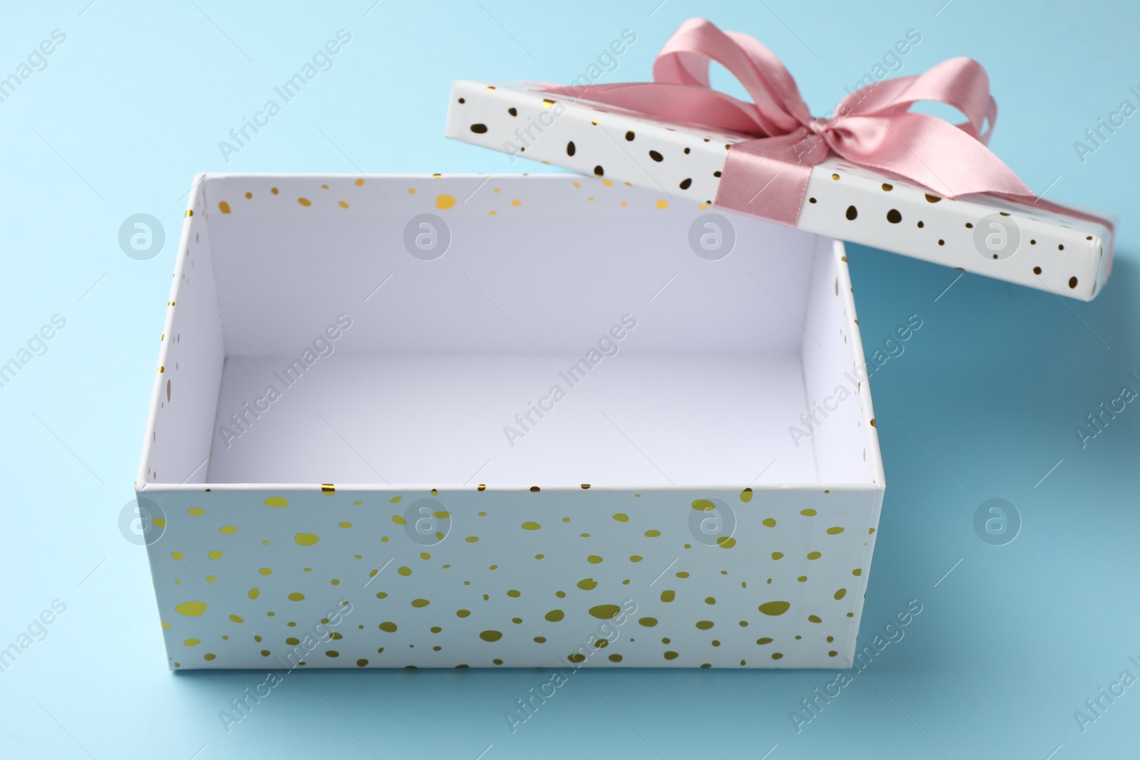 Photo of Opened gift box with beautiful lid on light blue background, closeup