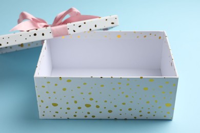Photo of Opened gift box with beautiful lid on light blue background, closeup