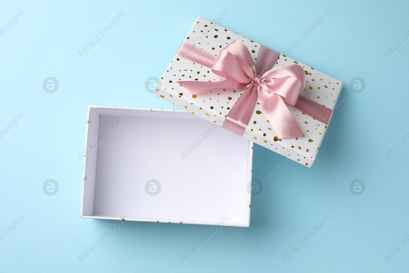 Opened gift box with beautiful lid on light blue background, top view Photo of Opened gift box with beautiful lid on light blue background, top view