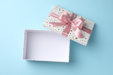 Photo of Opened gift box with beautiful lid on light blue background, top view