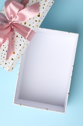 Photo of Opened gift box with beautiful lid on light blue background, top view