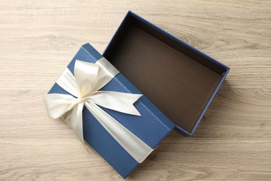 Photo of Opened gift box with beautiful lid on light wooden table, top view