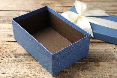 Photo of Opened gift box with beautiful lid on wooden table, closeup