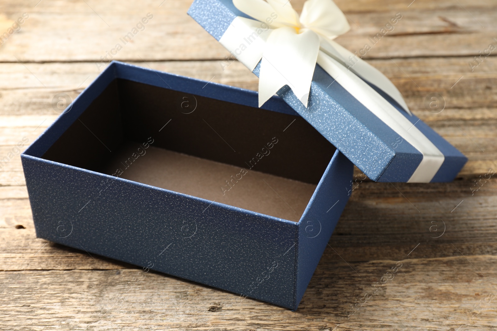 Photo of Opened gift box with beautiful lid on wooden table, closeup