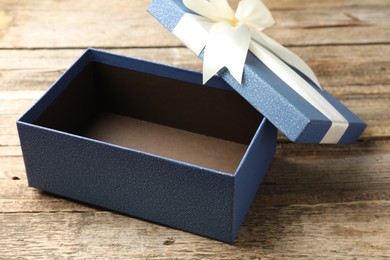 Photo of Opened gift box with beautiful lid on wooden table, closeup