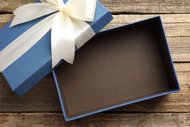 Photo of Opened gift box with beautiful lid on wooden table, top view