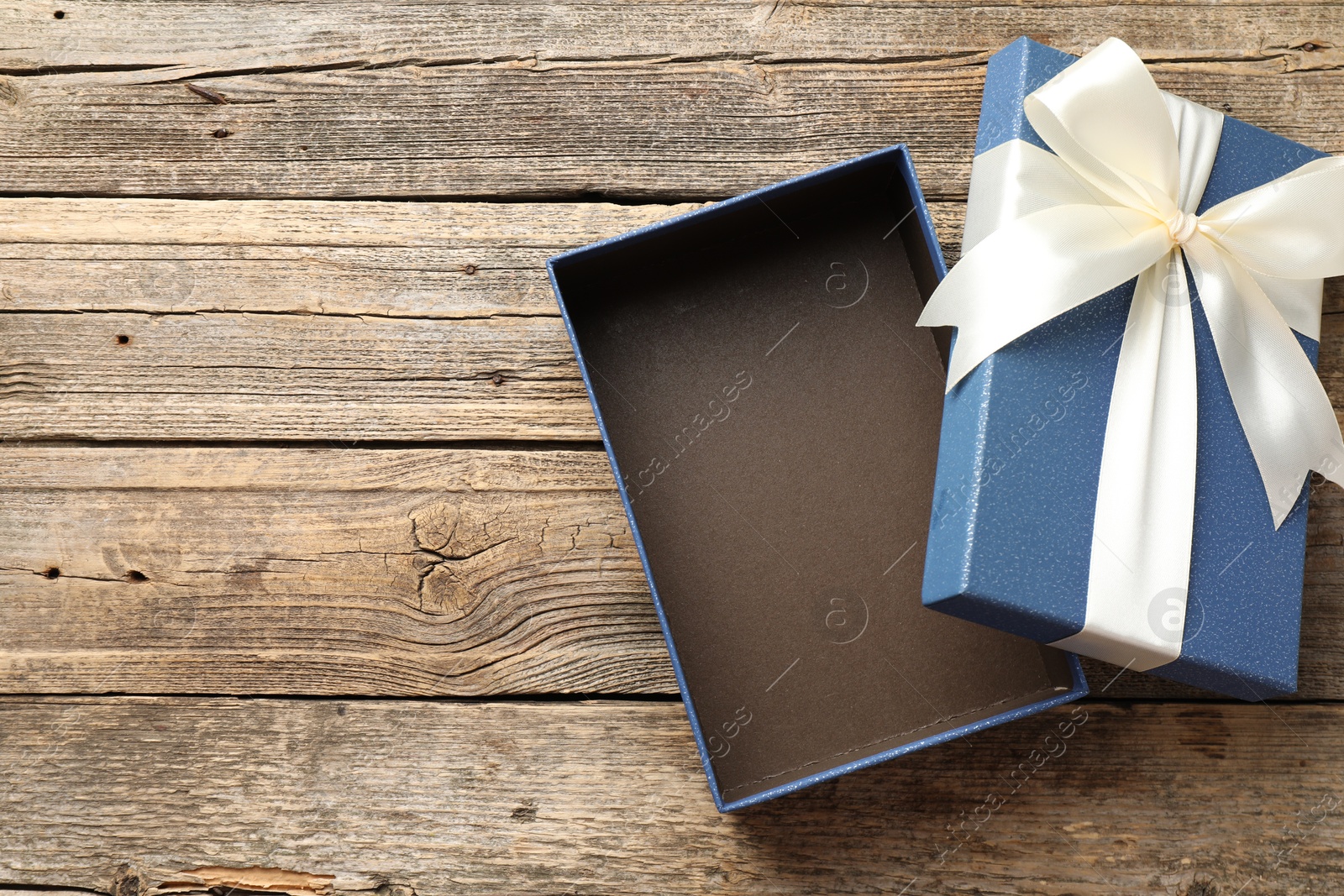 Photo of Opened gift box with beautiful lid on wooden table, top view. Space for text