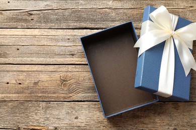 Photo of Opened gift box with beautiful lid on wooden table, top view. Space for text