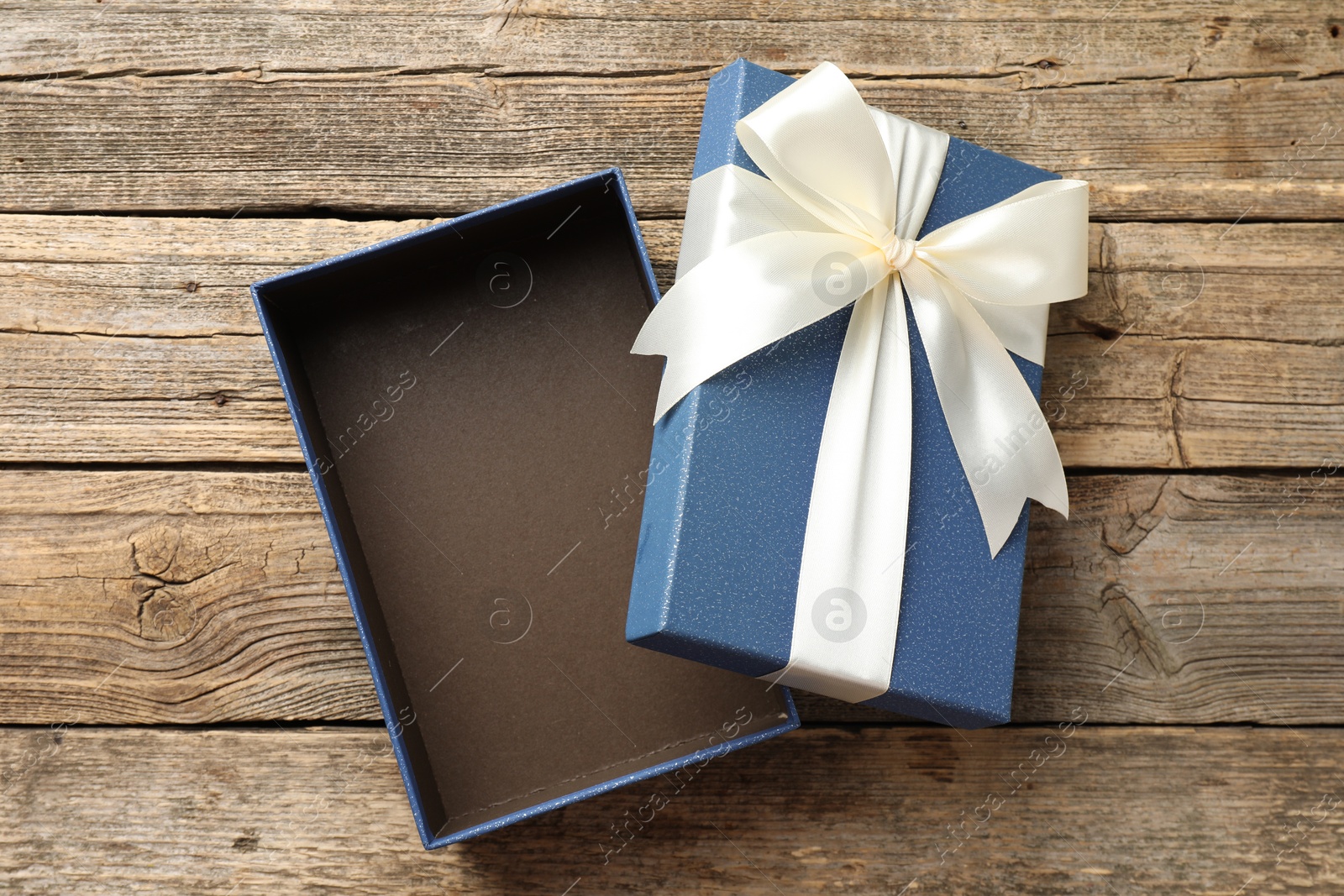 Photo of Opened gift box with beautiful lid on wooden table, top view
