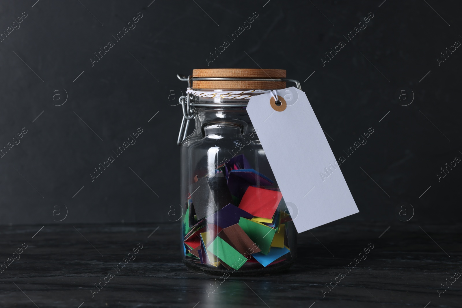 Photo of Colorful paper notes in glass jar with blank card on black table