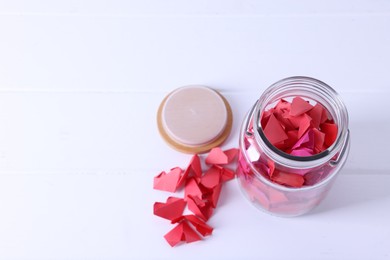 Photo of Message notes. Colorful paper pieces in glass jar on white table, above view. Space for text