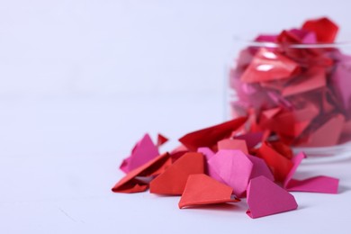 Photo of Message notes. Colorful paper pieces in glass jar on white table, closeup. Space for text