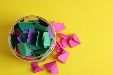 Photo of Colorful paper notes in glass jar on yellow background, top view. Space for text