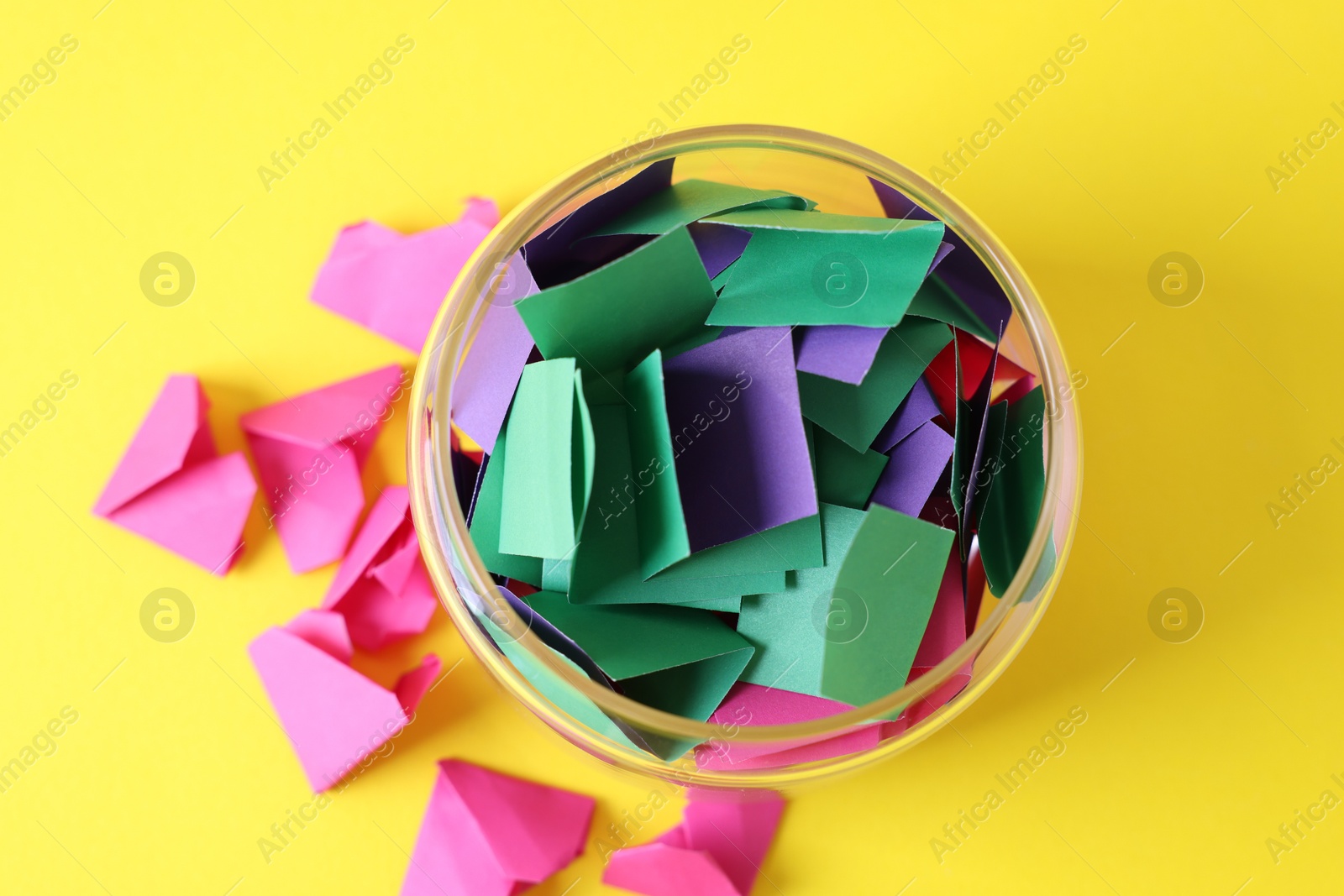 Colorful paper notes in glass jar on yellow background, top view Photo of Colorful paper notes in glass jar on yellow background, top view